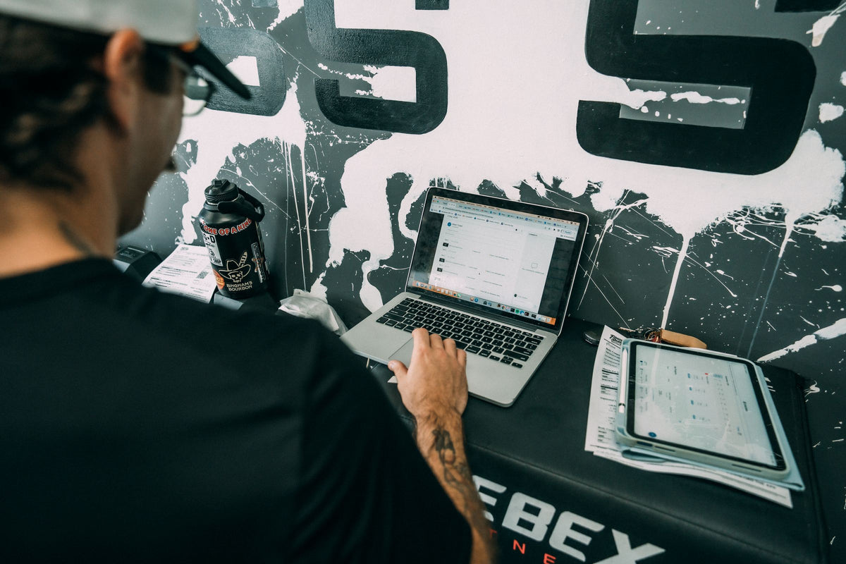 Coach writing a custom training program on a laptop