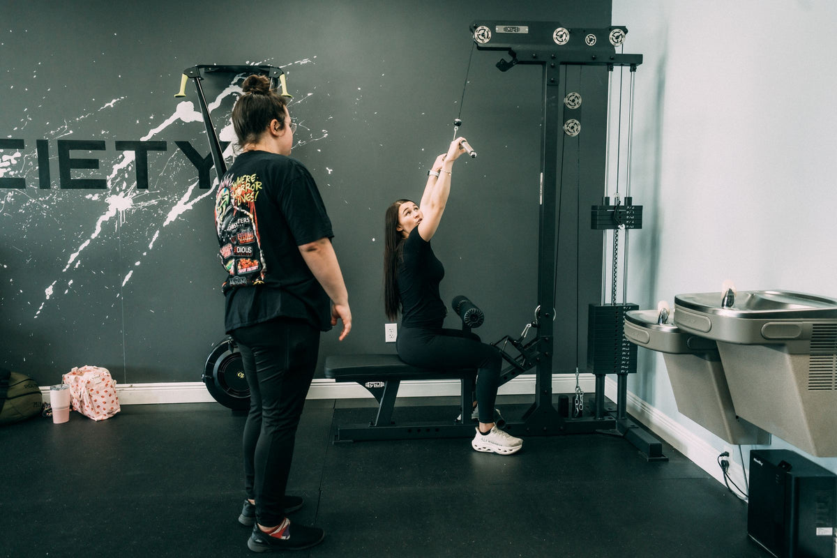 Client training on the cable machine with a coach watching