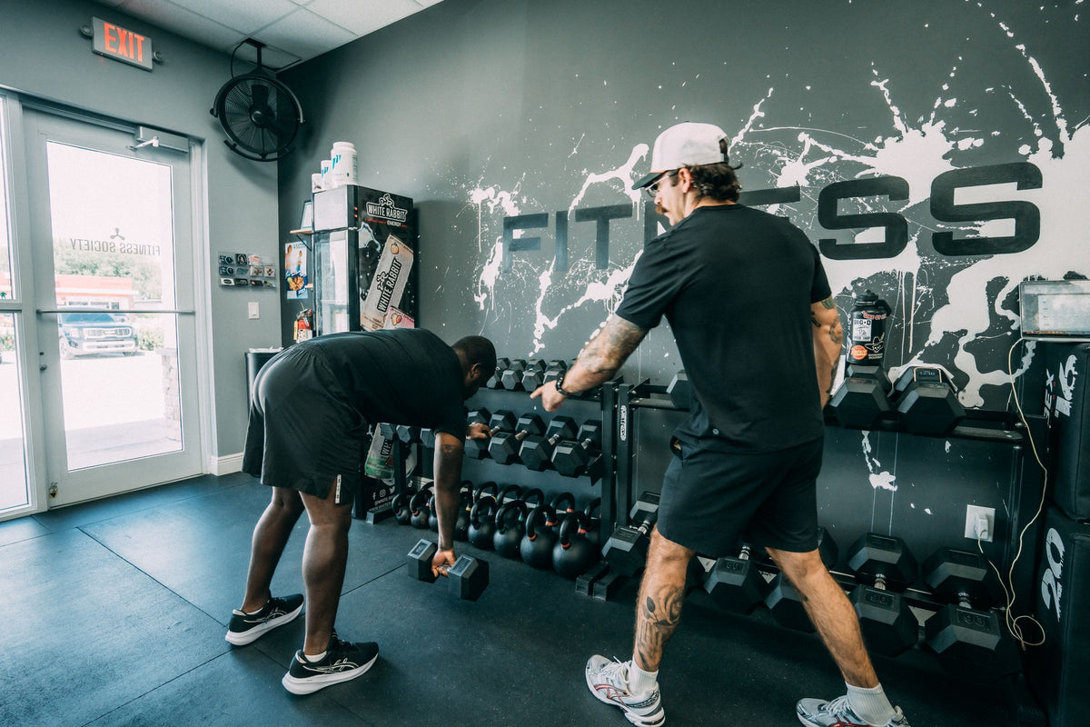 Coach and client selecting dumbbells from the studio rack