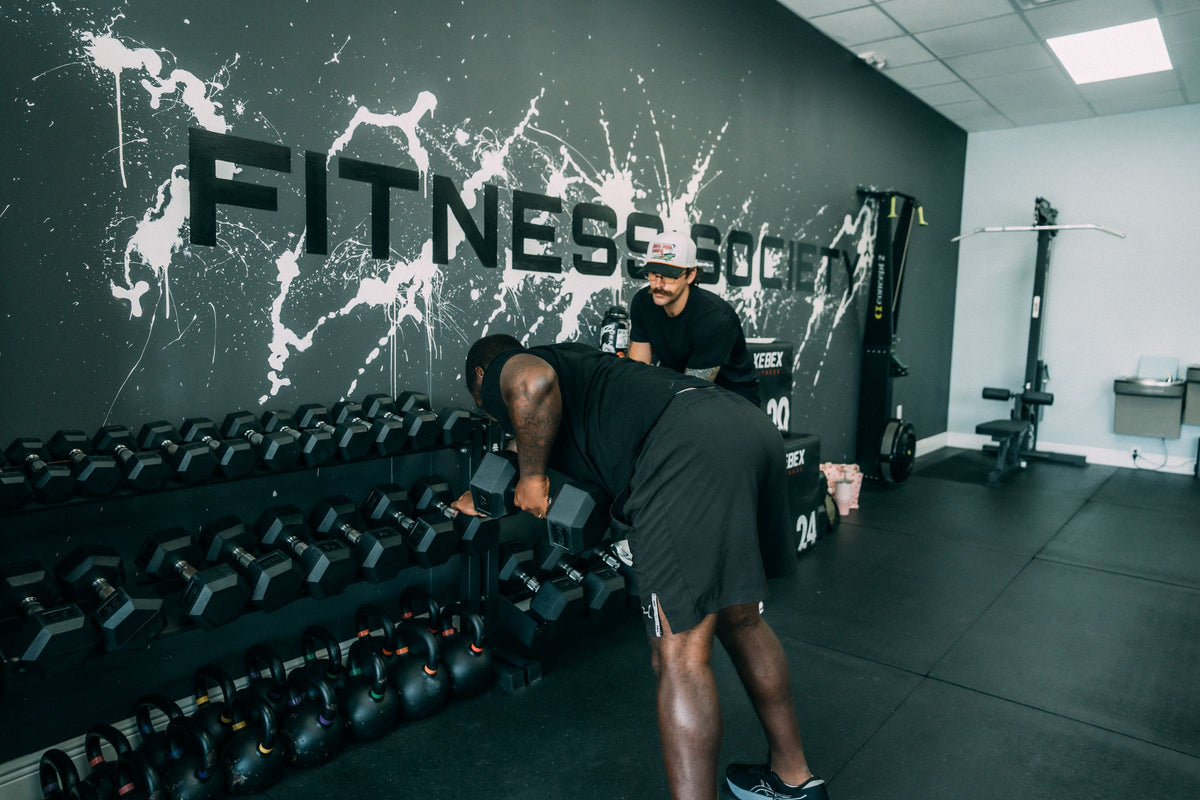 Dumbbell wall under the Fitness Society logo at the training studio