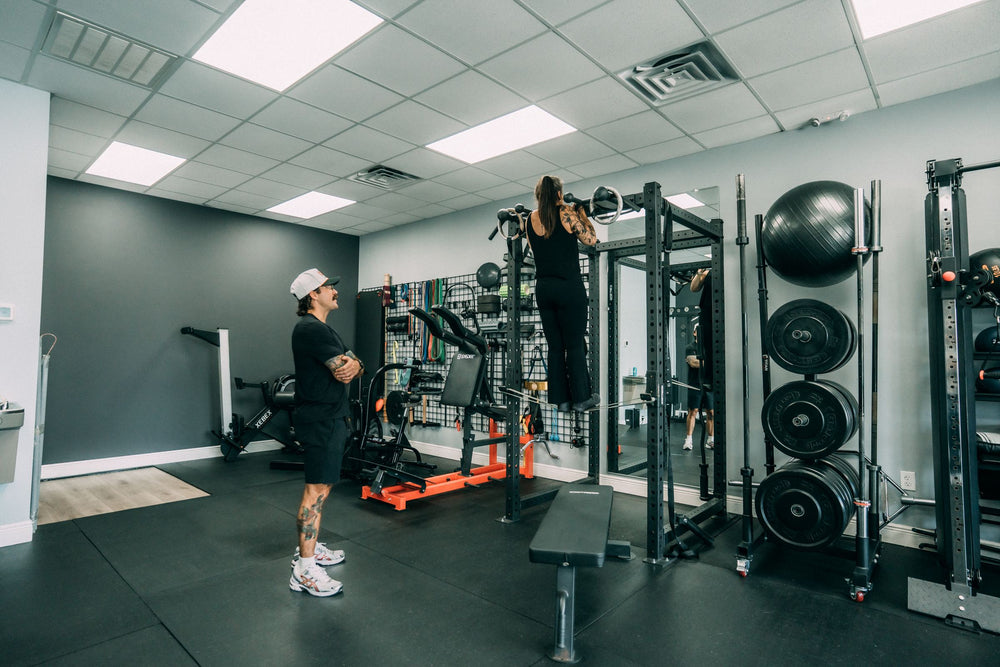 Client training at the squat rack while her coach watches