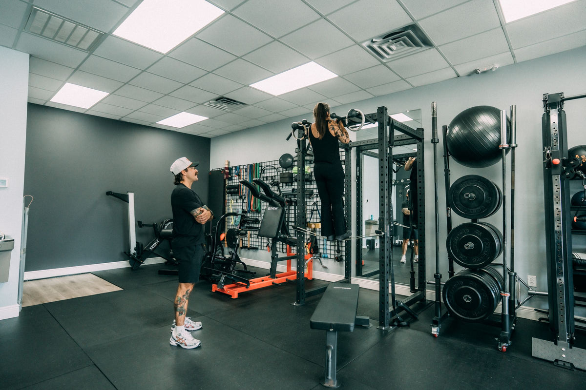 Client training at the squat rack while her coach watches